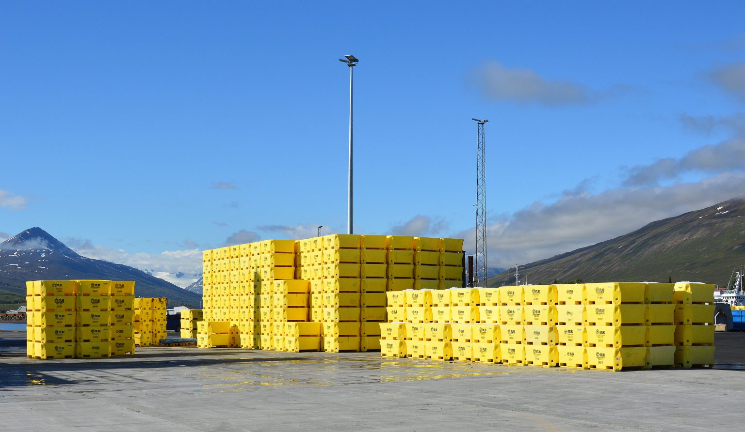 Yellow iTUB reusable containers stacked at an Icelandic harbour.